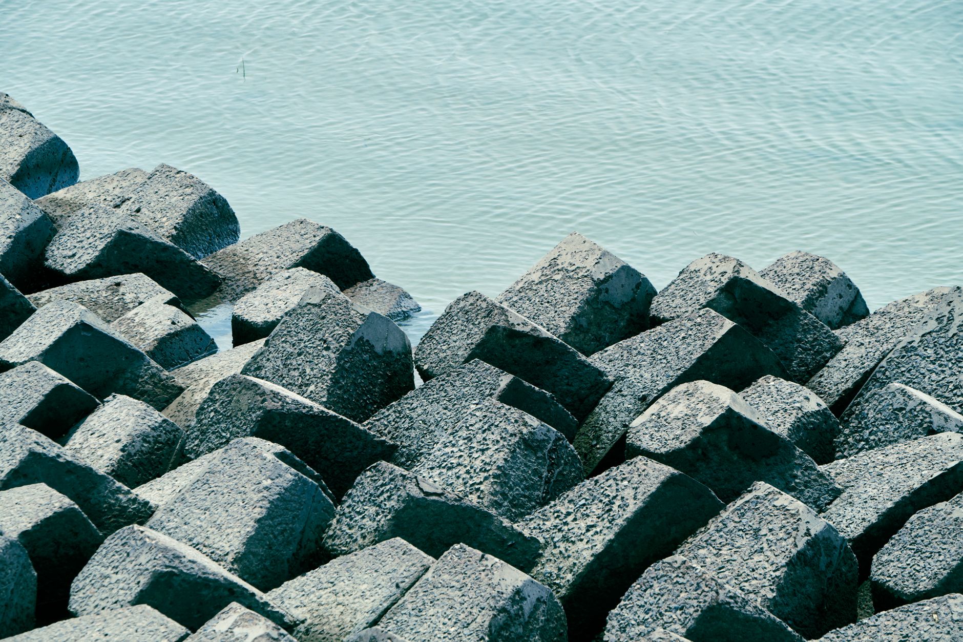 Concrete blocks at the shoreline protect against erosion, calm sea in view.
