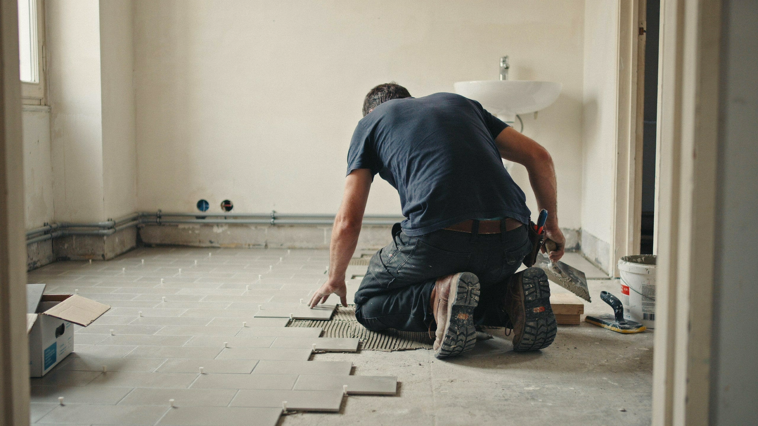 Carreleur posant un revêtement dans une pièce en rénovation