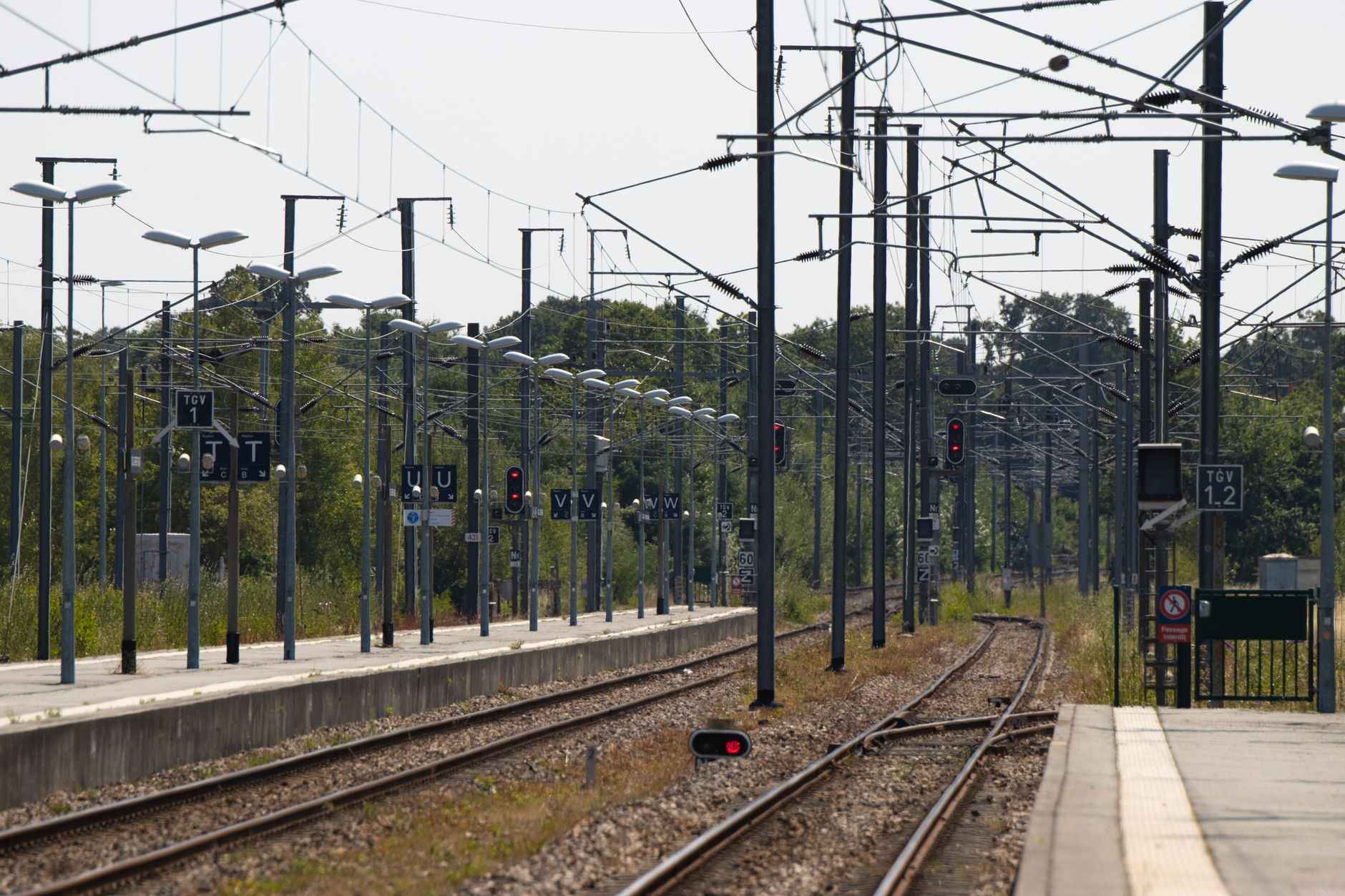 Quiet train tracks at Dol-de-Bretagne station, Brittany, France, with overhead power lines.